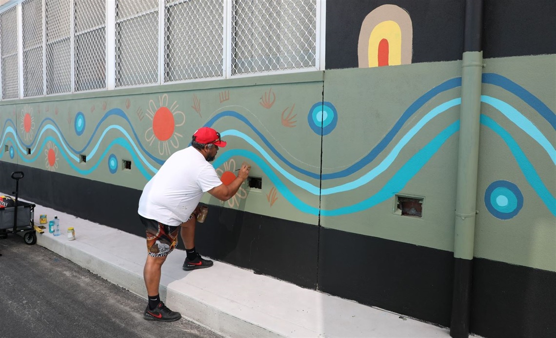 a mural artist painting a laneway