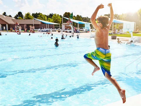 a boy jumping into a pool