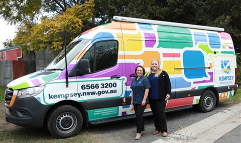 two women standing in front of a van