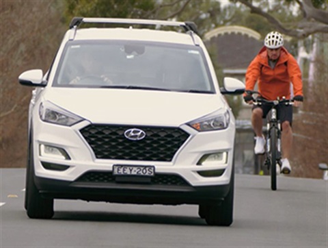 cyclist riding on road next to car