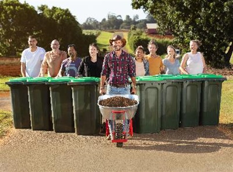 community with green bins behind farmer with barrow of compost