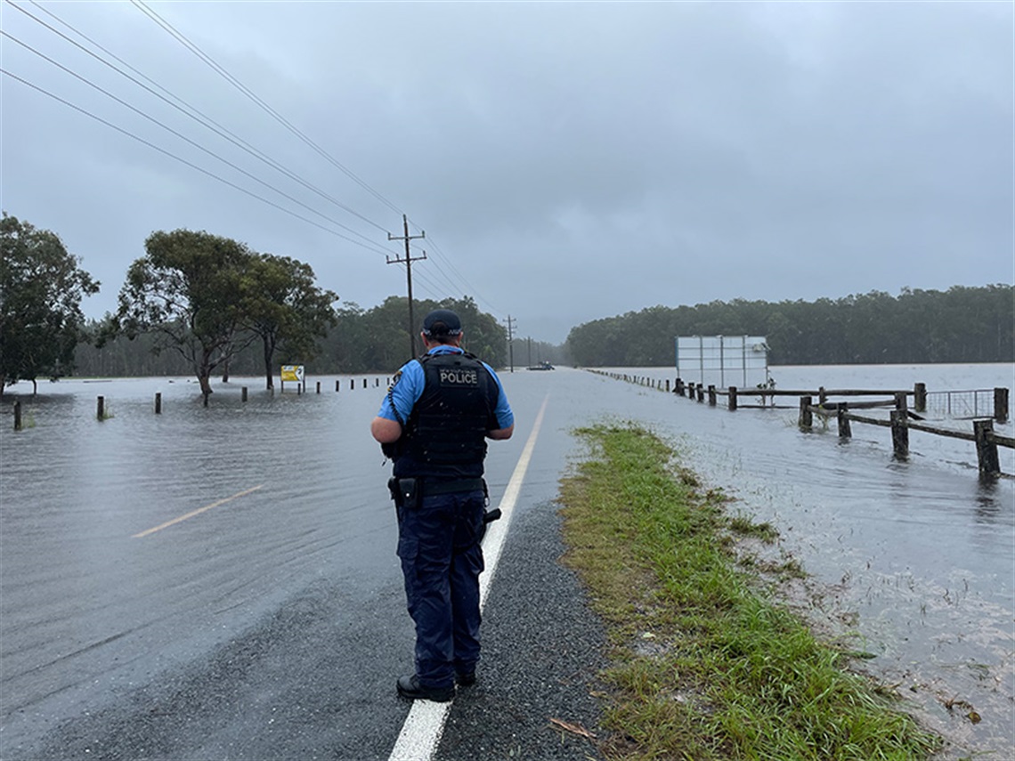 a police officer standing in front of a flooded road