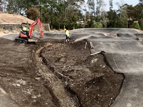 Workers preparing the pump track area for landscaping